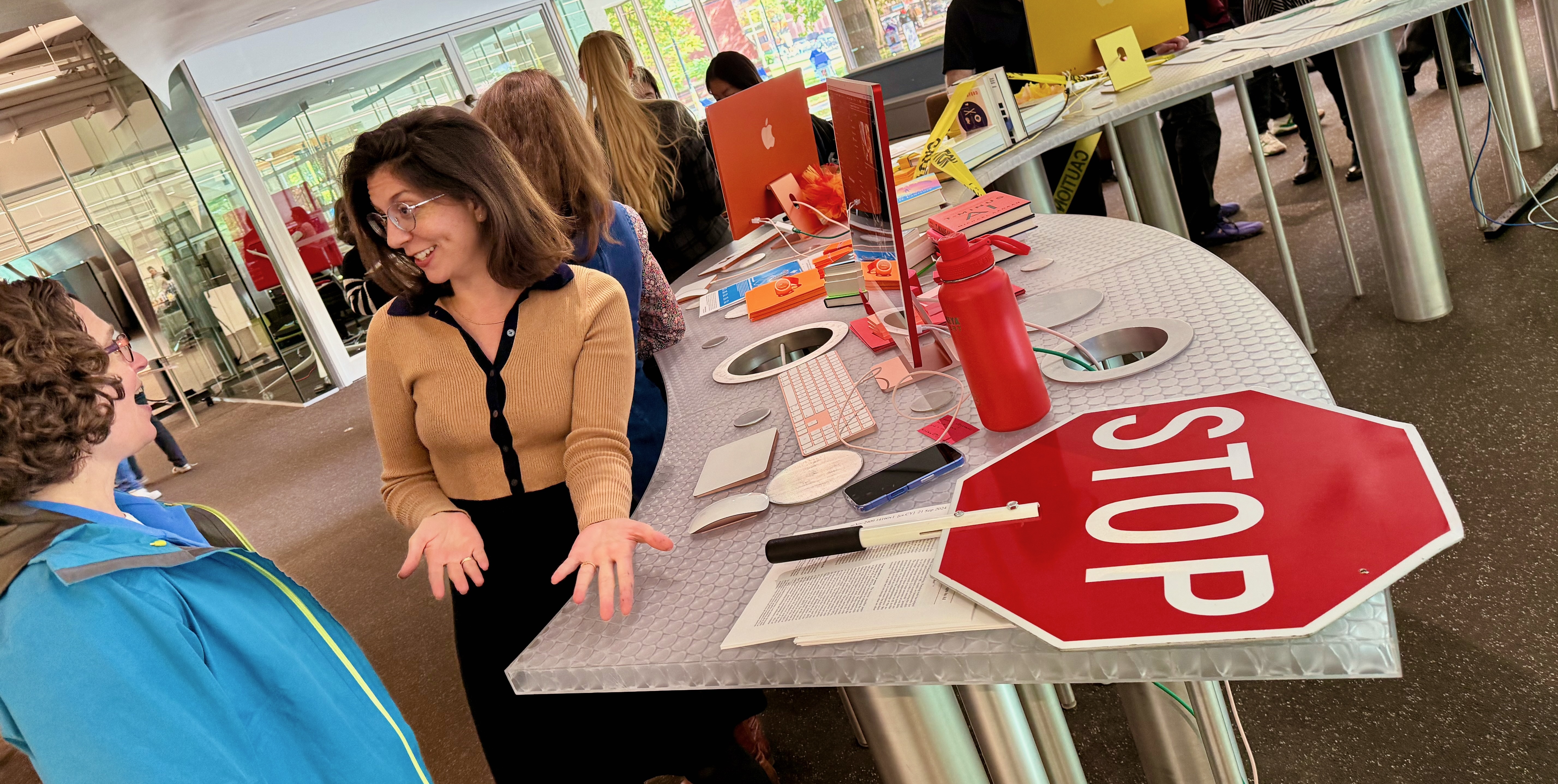 Learning Lab staff speaking excitedly to another person, in front of a red computer with a large red stop sign on the tabletop