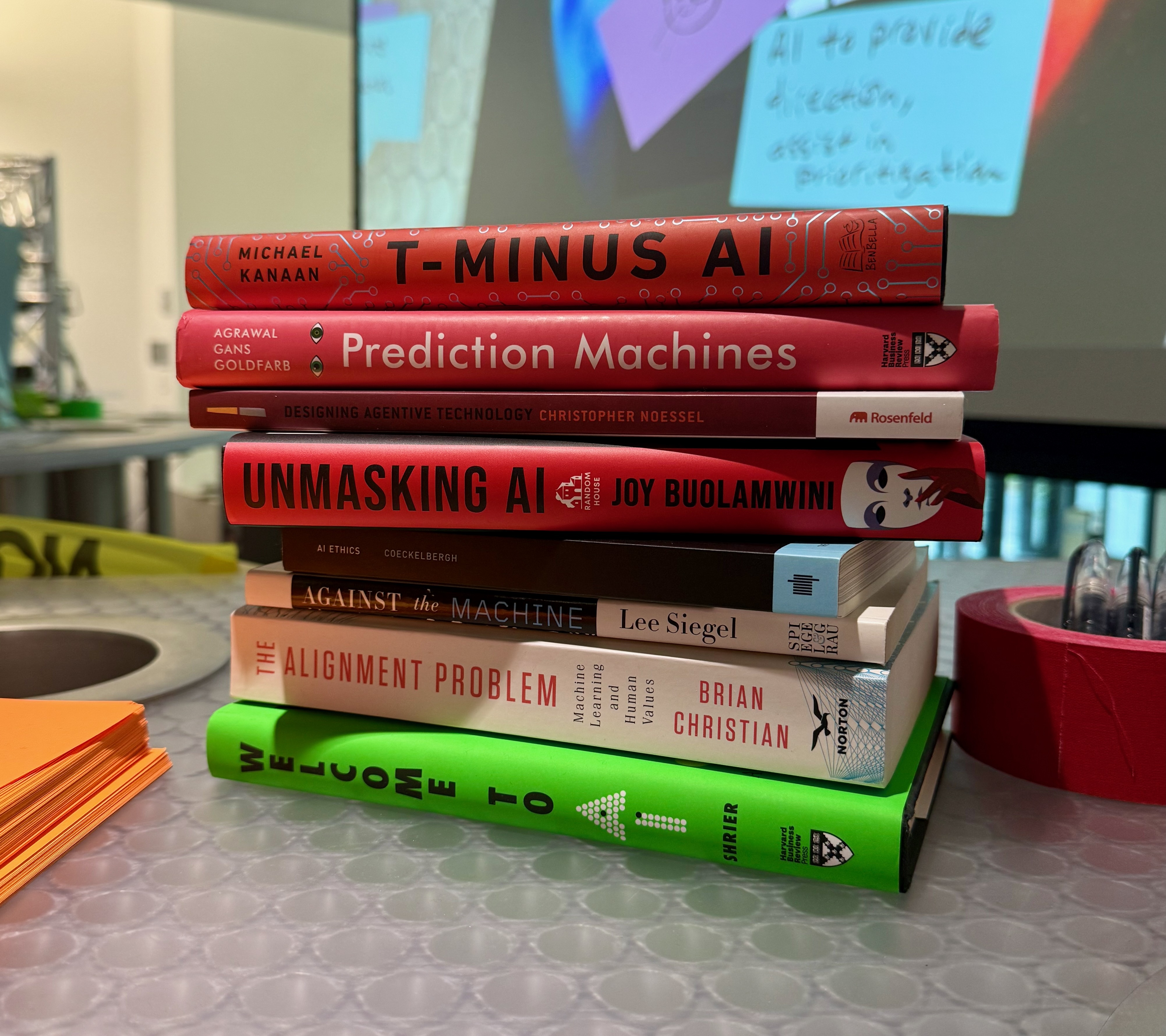 a stack of books about AI and ethics on top of a tabletop