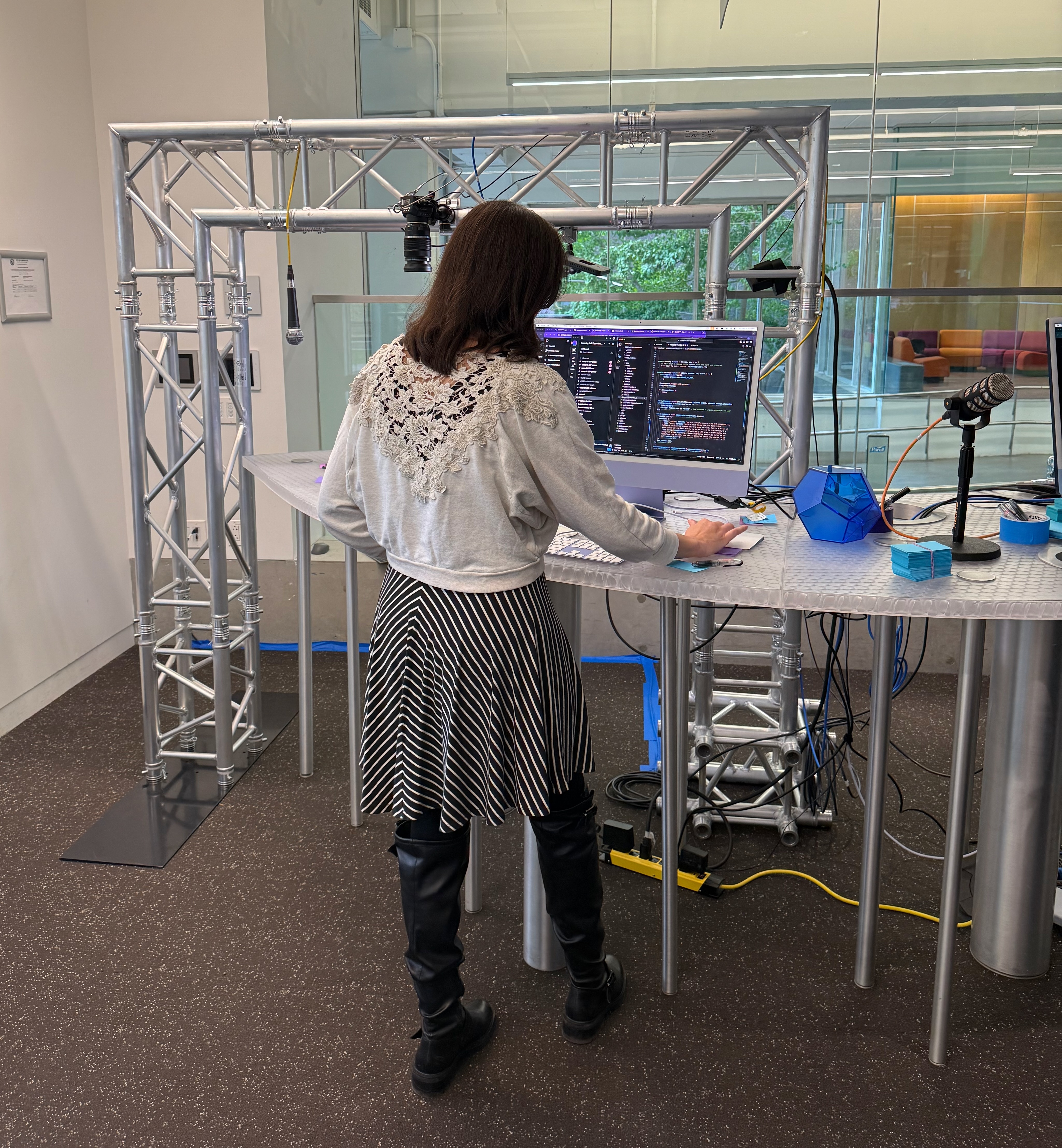Learning Lab staff working at a purple computer in front of truss that arches over the table