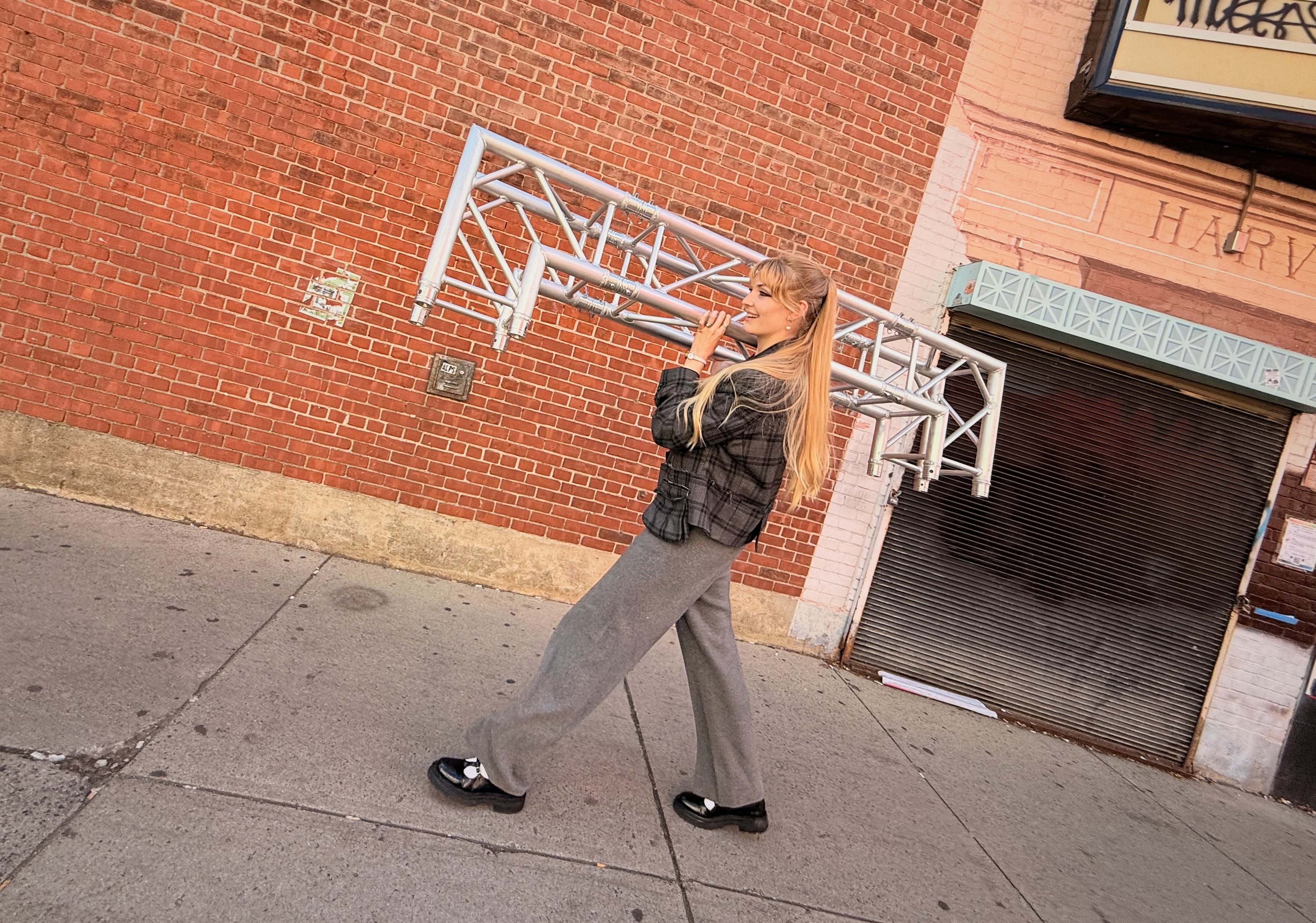 Madeleine carrying a large piece of truss down a sidewalk on Church Street