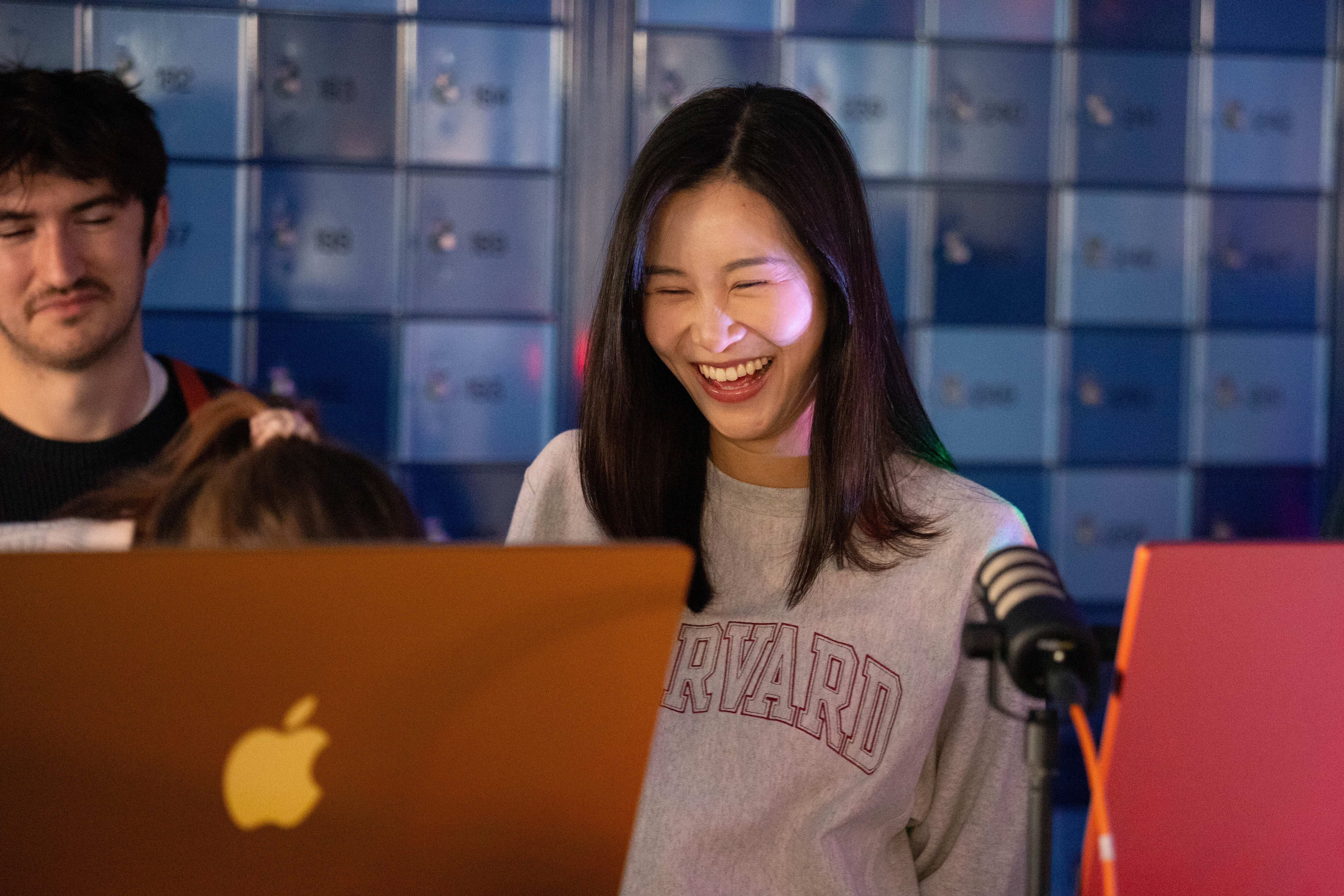 a student laughs at the audio reading of a poem she generated at the second station